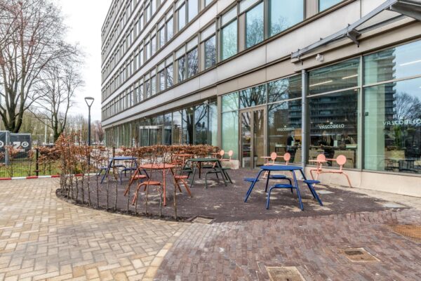 Terras met kleurrijke tafels en stoelen bij café Vascobelo aan de Vliegend Hertlaan.